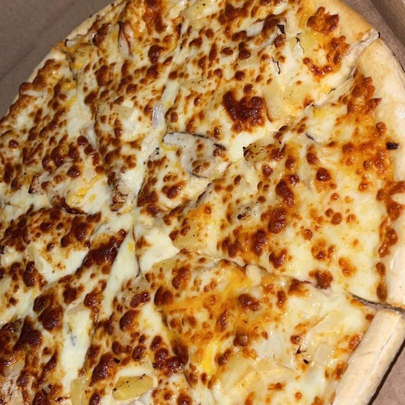 A close-up of a Joe's Pizza pie, generously topped with melted cheese and golden-brown crust.